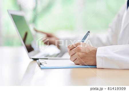 パソコンで調べてメモをする男性医師 81419309