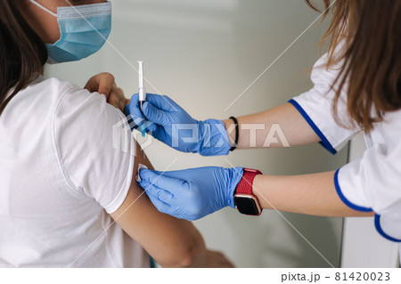 Woman in medical face mask getting Covid-19. Flu vaccine at the hospital. Professional nurse giving antiviral injection to female patient. Vaccination, disease prevention concept. Close-up of Woman in medical face mask getting Covid-19. Flu vaccine at the hospital. Professional nurse giving antiviral injection to female patient. Vaccination, disease prevention concept. Close-up of 81420023