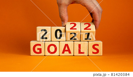 Planning 2022 goals new year symbol. Businessman turns wooden cubes and changes words 'Goals 2021' to 'Goals 2022'. Beautiful orange background, copy space. Business, 2022 goals new year concept. 81420384