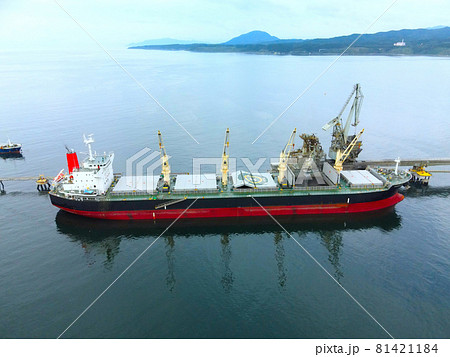 夏の北海道北斗市でセメント工場に荷物の積み下ろしをする貨物船の風景を空撮 81421184