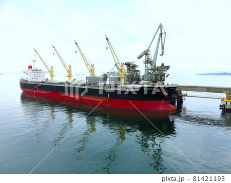 夏の北海道北斗市でセメント工場に荷物の積み下ろしをする貨物船の風景を空撮 81421193