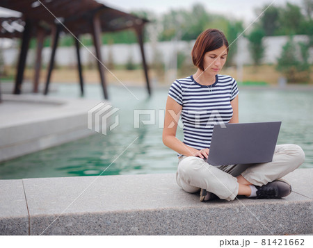 female student working with laptop in campus park. 81421662