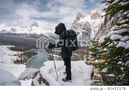 Photographer man standing with trekking poles on snow peak with mountain and lake view on Opabin Plateau at Yoho national park Photographer man standing with trekking poles on snow peak with mountain and lake view on Opabin Plateau at Yoho national park 81422178