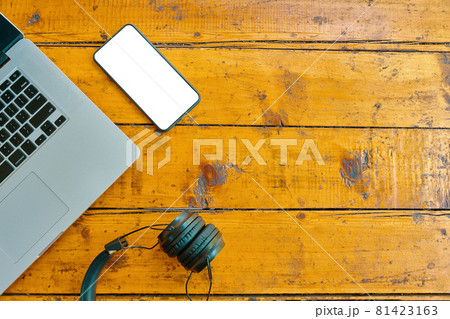 Flat lay of laptop, wireless headphones and mobile phone on wooden table. Flat lay of laptop, wireless headphones and mobile phone on wooden table. 81423163
