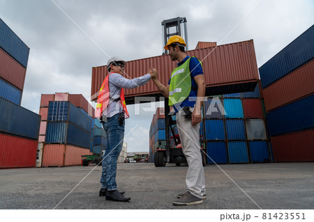 Industrial worker works with co-worker at overseas shipping container yard 81423551