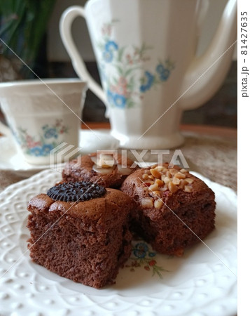 A chocolate nut cake on a plate in front of a tea set A chocolate nut cake on a plate in front of a tea set 81427635