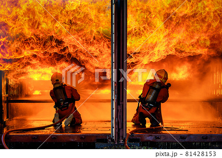 Team of two firefighters wearing full uniform with oxygen tank on back holding pipe spread water and face to wide huge orange hot fire with brave and responsibility in narrow disaster burn area Team of two firefighters wearing full uniform with oxygen tank on back holding pipe spread water and face to wide huge orange hot fire with brave and responsibility in narrow disaster burn area 81428153