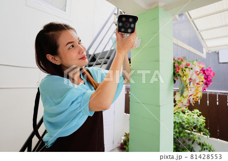 Beautiful woman house adjusts direction angle view of CCTV home security camera and fine-tune internet cam for perfect scene of watching. Conept for self-reliant and DIY job of modern housewife. Beautiful woman house adjusts direction angle view of CCTV home security camera and fine-tune internet cam for perfect scene of watching. Conept for self-reliant and DIY job of modern housewife. 81428553