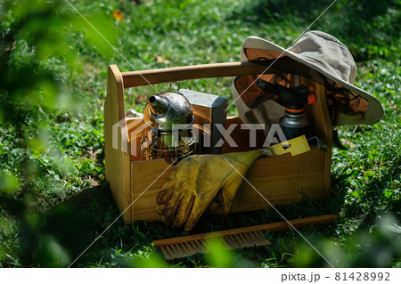A tool of the beekeeper. Everything for a beekeeper to work with bees. Smoker, a chisel, a box, beekeeper suit for protection from the bees. Beekeeping equipment. Photo on the topic of beekeeping. A tool of the beekeeper. Everything for a beekeeper to work with bees. Smoker, a chisel, a box, beekeeper suit for protection from the bees. Beekeeping equipment. Photo on the topic of beekeeping. 81428992