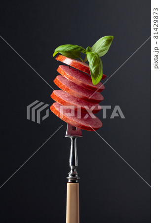 Sliced smoked sausage with green basil leaves. Sliced smoked sausage with green basil leaves. 81429873