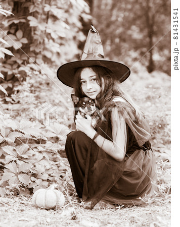 Little girl in halloween costume posing with pumpkin outdoor. Teenage girl with a dog. Little girl in halloween costume posing with pumpkin outdoor. Teenage girl with a dog. 81431541