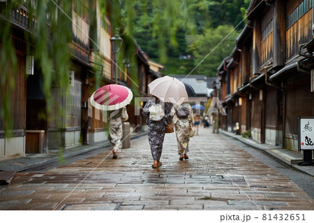 雨のひがし茶屋街を着物を着た女性が傘をさして歩く 81432651