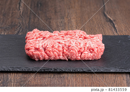 Minced meat on a slate stone board over a wooden background. 81433559