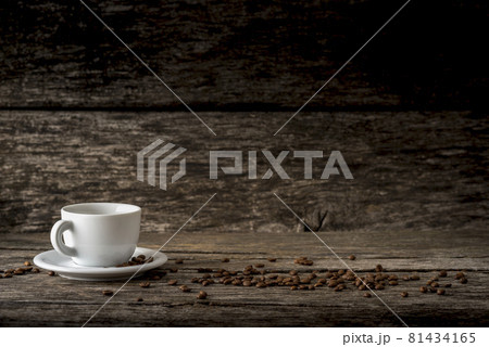 White coffee mug on a plate placed on a rustic wooden boards with coffee beans scattered around 81434165