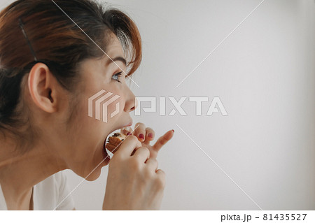 Close up face of woman bite a piece of bread on white background. 81435527