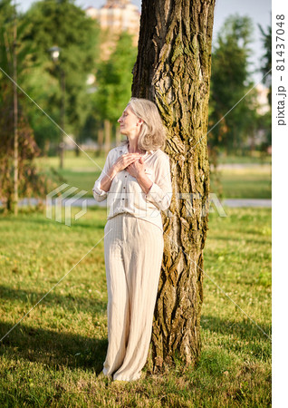 Woman with closed eyes leaning on tree Woman with closed eyes leaning on tree 81437048