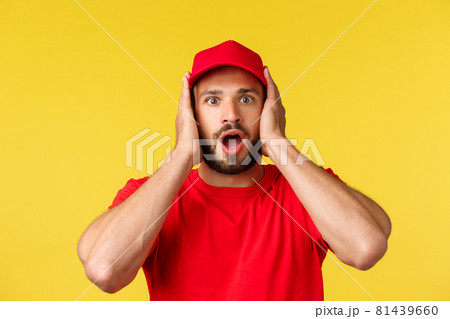 Close-up of shocked gasping male courier, employee in red uniform cap and t-shirt, cover ears and staring speechless at camera, heard stunning news, standing yellow background Close-up of shocked gasping male courier, employee in red uniform cap and t-shirt, cover ears and staring speechless at camera, heard stunning news, standing yellow background 81439660