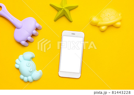 Mobile phone with white screen and plastic beach toy pastel color on yellow background. The development of fine motor concept. Creativity Game, technology and summer concept. Mobile phone with white screen and plastic beach toy pastel color on yellow background. The development of fine motor concept. Creativity Game, technology and summer concept. 81443228