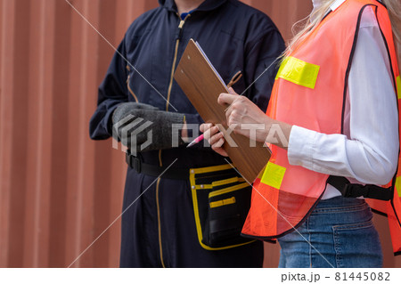 Industrial worker works with co-worker at overseas shipping container yard 81445082