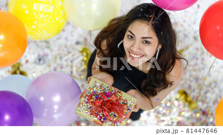 Two young and beautiful sexy Asian girls with colorful gift box dancing and playing with fun and happiness in a party with the bright color balloon in the background. Taken from a top-down angle. 81447646