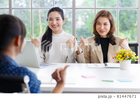 Deaf translator teaching two businesswomen to use and understand hand language sign 81447671