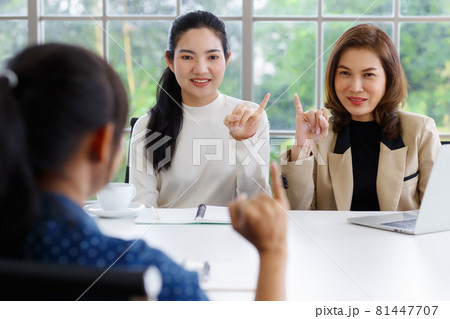 Deaf translator teaching two businesswomen to use and understand hand language sign 81447707