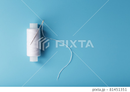 A skein of white thread with a needle on a blue background 81451351
