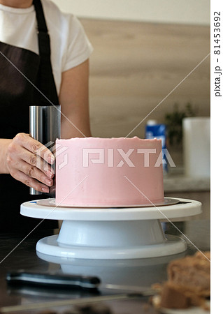 Woman pastry chef making chocolate cake with pink cream, close-up. Cake making process, Selective focus Woman pastry chef making chocolate cake with pink cream, close-up. Cake making process, Selective focus 81453692