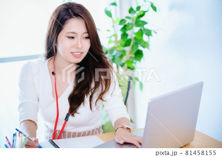 日差しがさしこむ明るいオフィスでノートパソコンを使う若い女性 日差しがさしこむ明るいオフィスでノートパソコンを使う若い女性 81458155