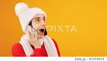 Wow offer. Surprised lady in winter outfit talking on smartphone and looking at free space on yellow background Wow offer. Surprised lady in winter outfit talking on smartphone and looking at free space on yellow background 81459039