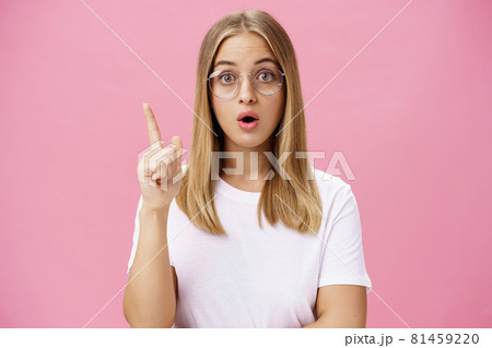 One more thing need said. Intelligent and smart female A student in glasses and white t-shirt open mouth and folding lips raising index finger in eureka gesture adding suggestion, having idea 81459220
