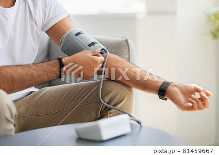 Unrecognizable male patient using modern tonometer at home Unrecognizable male patient using modern tonometer at home 81459667