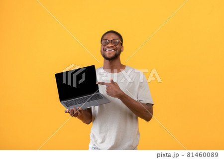 Joyful black man pointing at blank laptop screen with space for your website design over yellow background, mockup Joyful black man pointing at blank laptop screen with space for your website design over yellow background, mockup 81460089