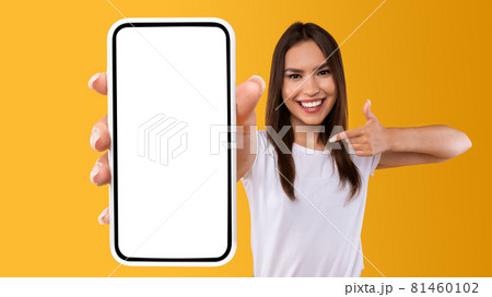 Woman showing white empty smartphone screen and pointing 81460102