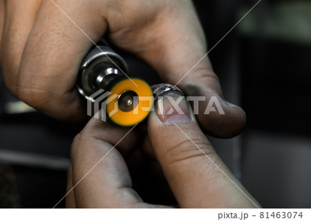 Hands of the jeweler polishes ring on the polishing machine. Goldsmith working on his workbench 81463074