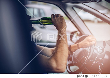 Man drinking beer while driving a car. 81468005