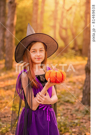 Halloween concept. Girl dressed as witch holding pumpkin in her hands on forest background. Halloween concept. Girl dressed as witch holding pumpkin in her hands on forest background. 81469638