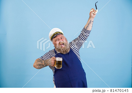Excited obese man sailor holds beer and raises up pipe on light blue background 81470145