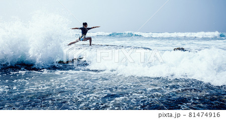 Woman practice yoga at seaside cliff edge facing the coming strong sea waves Woman practice yoga at seaside cliff edge facing the coming strong sea waves 81474916