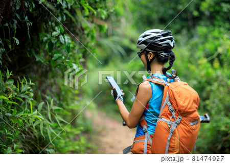 Woman cyclist use smartphone when riding mountain bike on forest trail 81474927