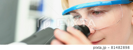 Woman chemist in safety glasses looking through microscope Woman chemist in safety glasses looking through microscope 81482898