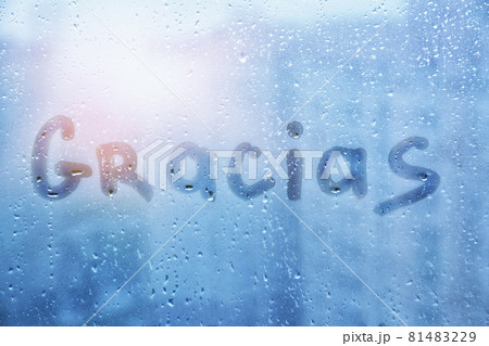 spanish word Gracias are painted on wet blue glass of window on sunset spanish word Gracias are painted on wet blue glass of window on sunset 81483229