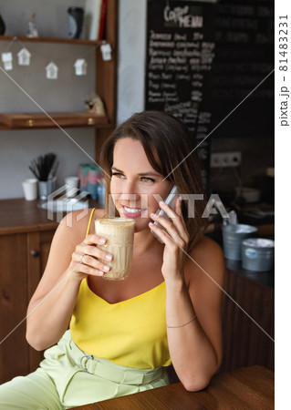 portrait of smiling woman with cup of coffee in her hand and talking o smartphone portrait of smiling woman with cup of coffee in her hand and talking o smartphone 81483231