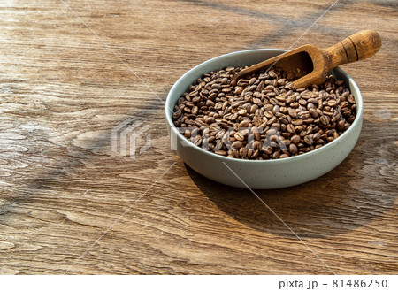 Coffee beans with old wooden scoop on the ceramic plate put on wooden background. Coffee beans with old wooden scoop on the ceramic plate put on wooden background. 81486250