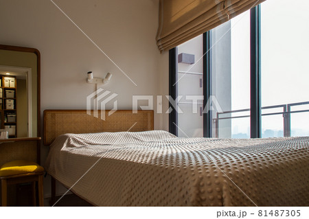 Interior white bedroom with brown curtains and white pillows, blanket on wooden bed classic illuminated by sunlight in the morning. 81487305