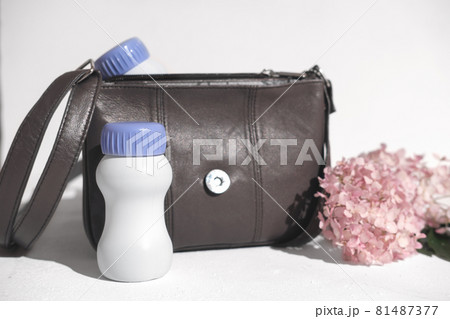 white plastic bottle next to handbag and flowers. collagen or protein drink to go. liquid protein for wellness, skin beauty and healthy joints. healthcare supplement white plastic bottle next to handbag and flowers. collagen or protein drink to go. liquid protein for wellness, skin beauty and healthy joints. healthcare supplement 81487377