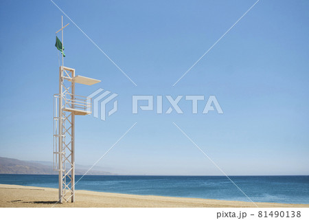 aid station on a beach with calm sea on sunny day and green flag 81490138