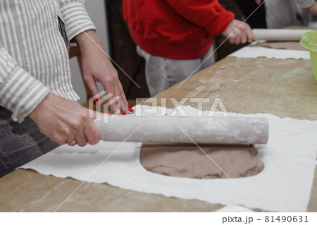 Women's hands knead clay, drawing elements of the product. Production of ceramic products at the master class on ceramics. Women's hands knead clay, drawing elements of the product. Production of ceramic products at the master class on ceramics. 81490631