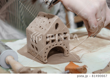 Women's hands knead clay, drawing elements of the product. Production of ceramic products at the master class on ceramics. Women's hands knead clay, drawing elements of the product. Production of ceramic products at the master class on ceramics. 81490667