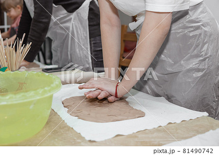 Women's hands knead clay, drawing elements of the product. Production of ceramic products at the master class on ceramics. 81490742